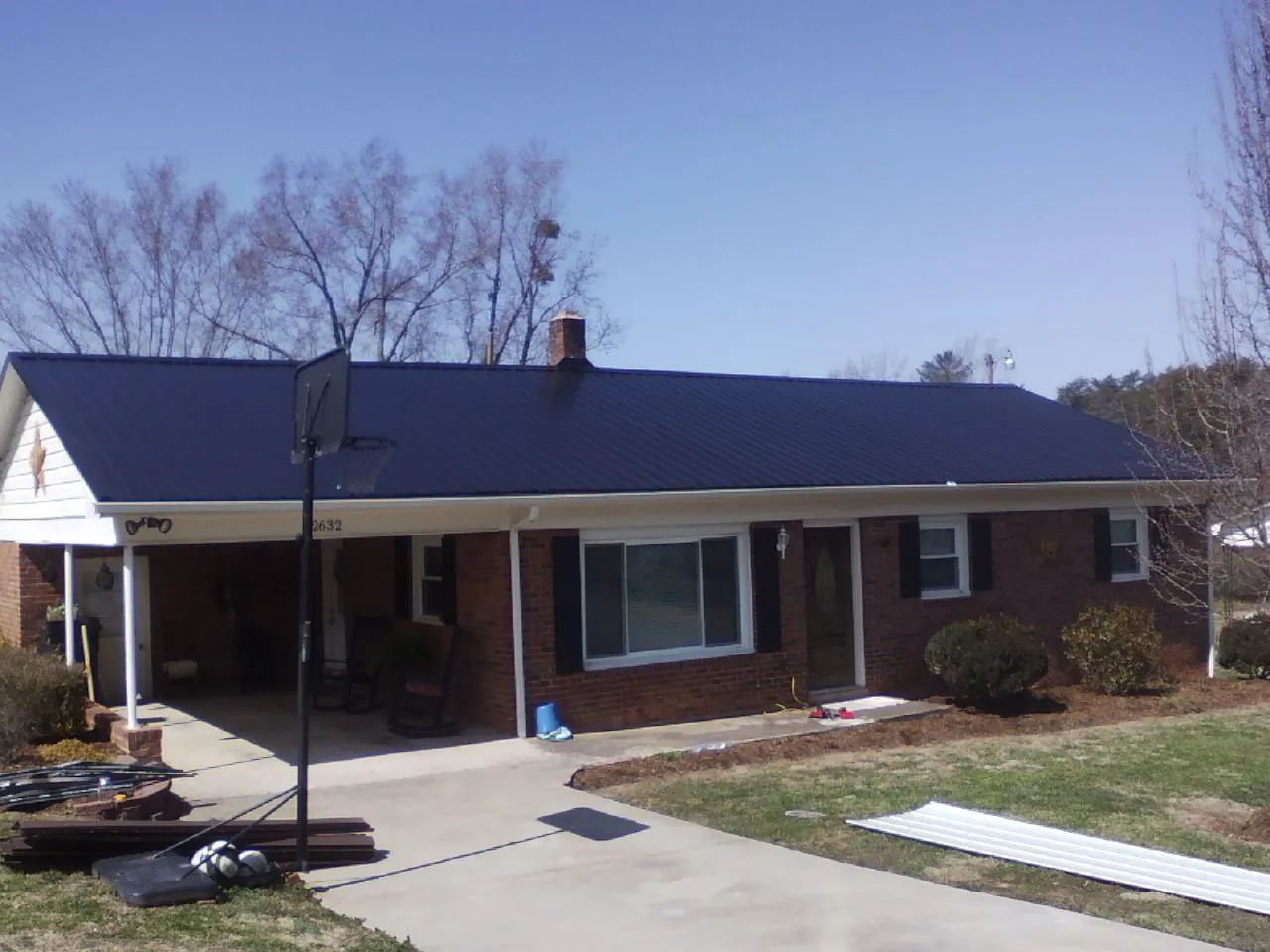 Finished dark blue metal roof on a brick ranch with a carport in Naples