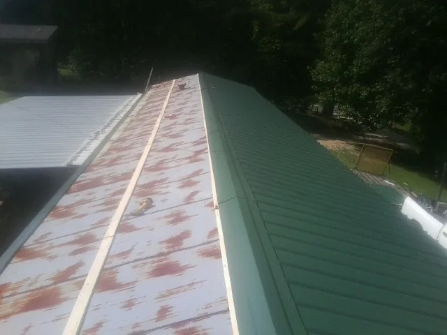 Old rusted panels beside newly installed green metal roofing — Wind Damage Roof Repair by Roofing Brothers in Naples
