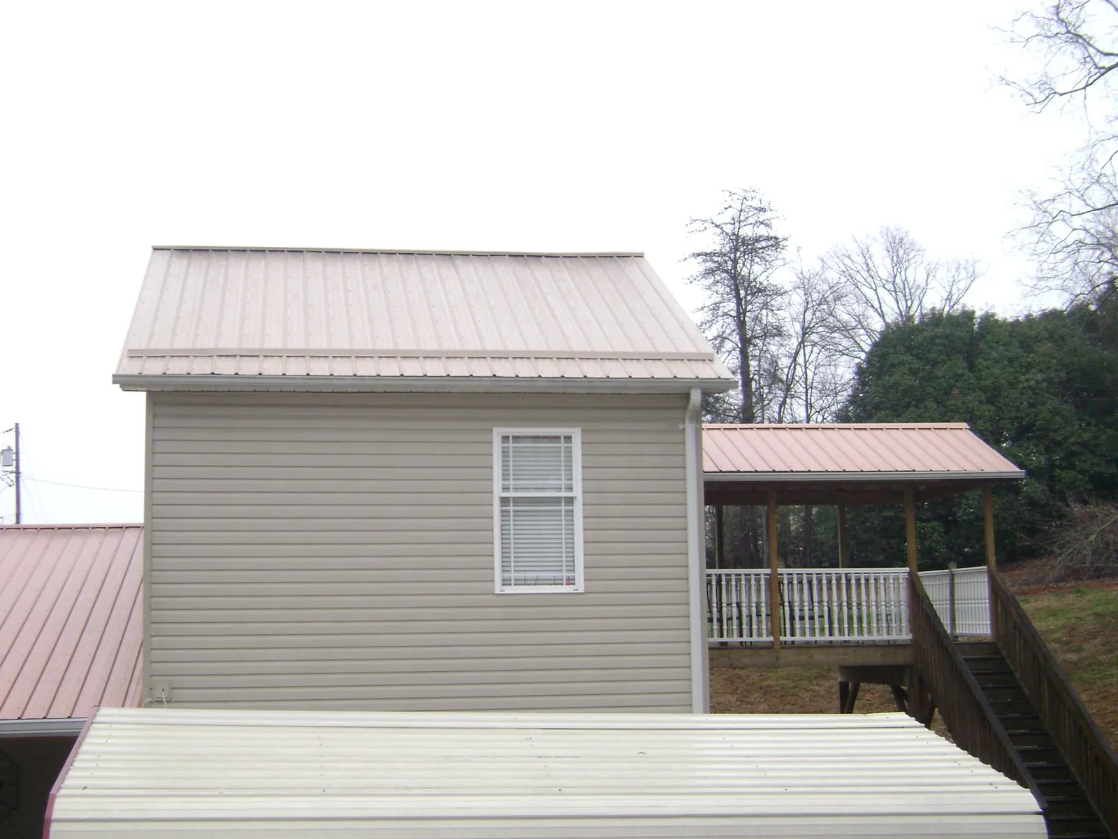 Tan metal roofs on a two story addition and attached porch, from a Roof Replacement job in Naples